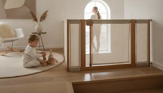 A toddler playing safely near an elegant beige fabric stair gate in a bright modern nursery