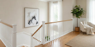 Bright home staircase with a banister, wall, and clear landing area