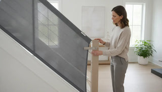 Parent inspecting an installed baby gate at a residential staircase