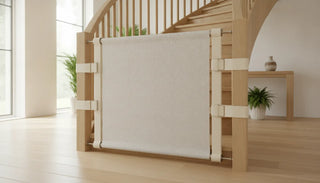 Fabric safety gate installed across a wooden staircase banister in a bright modern home