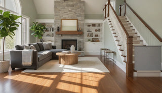 A premium fabric safety gate in Pebble Gray Linen elegantly installed at the bottom of a wooden staircase in a high-end living room.