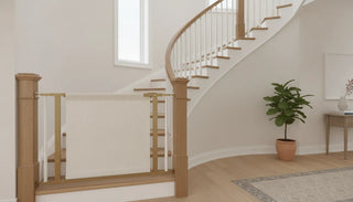 Fabric tall baby gate installed between staircase banisters