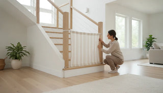 Fabric safety gate installed across a wide staircase with wooden banisters in a bright home