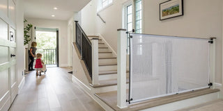 Retractable baby gate installed at the top of stairs in a modern home.