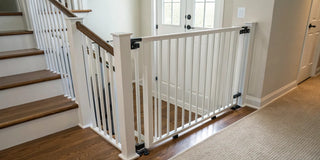 White hardware-mounted stair gate at the top of wooden stairs for child safety.