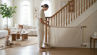 Fabric safety gate installed across a staircase with curved wooden banisters in a bright modern living room