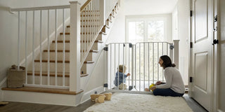 An infant safety gate installed at the bottom of a staircase to keep a child safe.