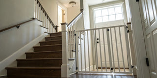 Extra tall stair gate installed at the bottom of wooden stairs for child safety.