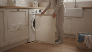A parent removing a fabric baby gate panel for cleaning in a modern laundry room